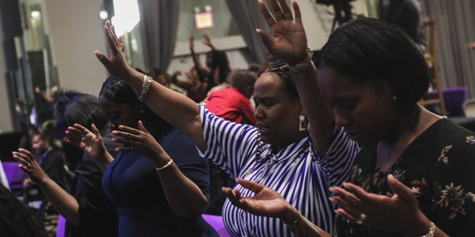 A minister laying hands on people in prayer at a R.A.W. gathering